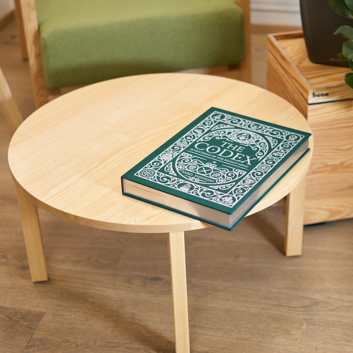 Round wooden table with a the codex book. Art book for coffee table.