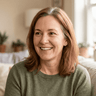 Portrait of a smiling middle-aged woman with shoulder-length reddish-brown hair in a green sweater.